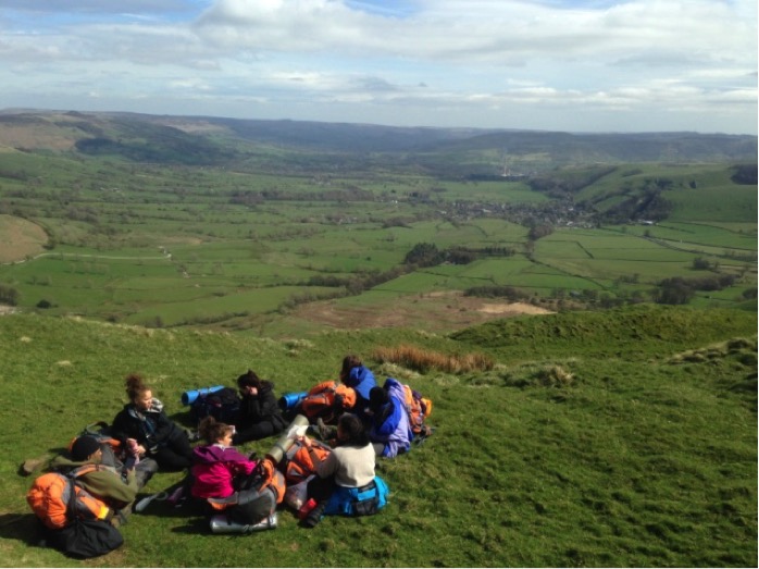 Group sitting on top of a hill relaxing with their kit bags 